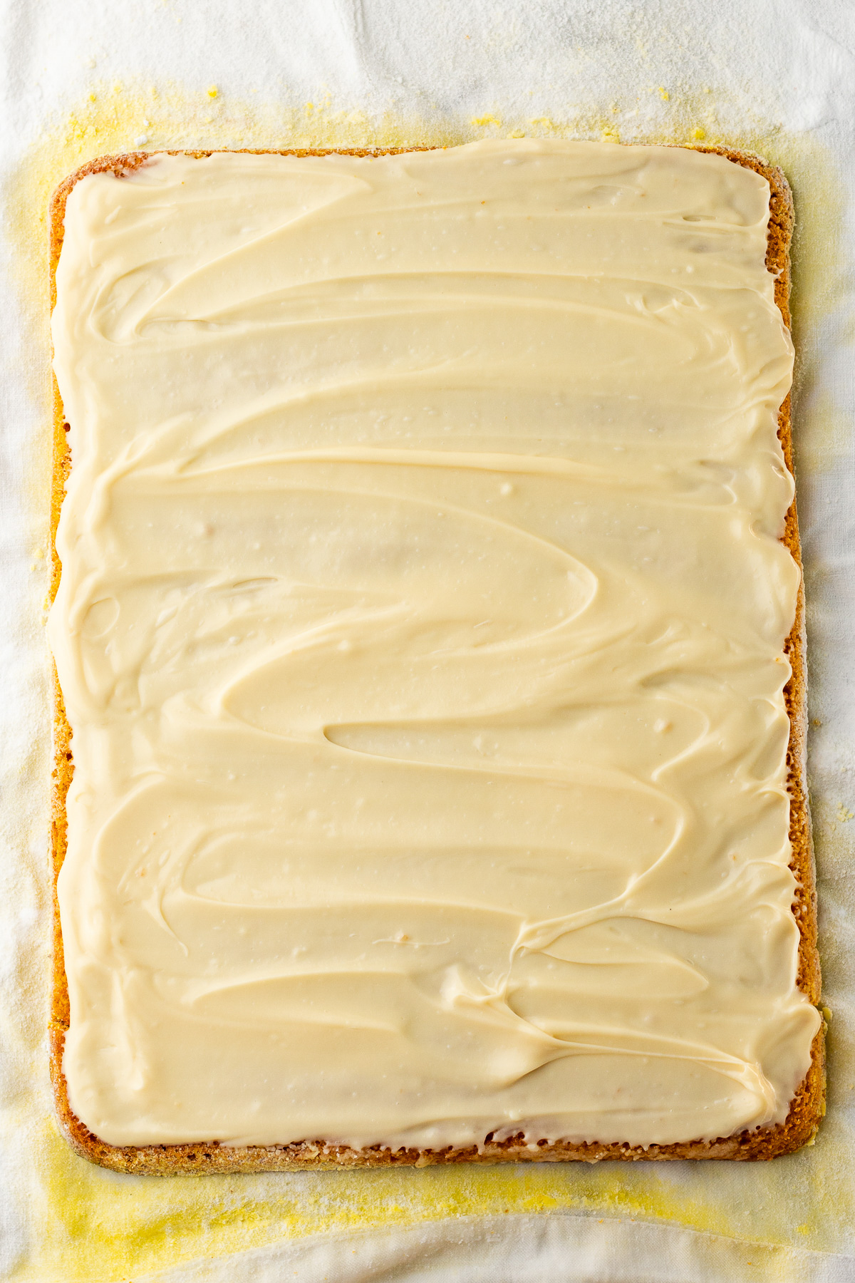 cream cheese filling spread on pumpkin roll cake.