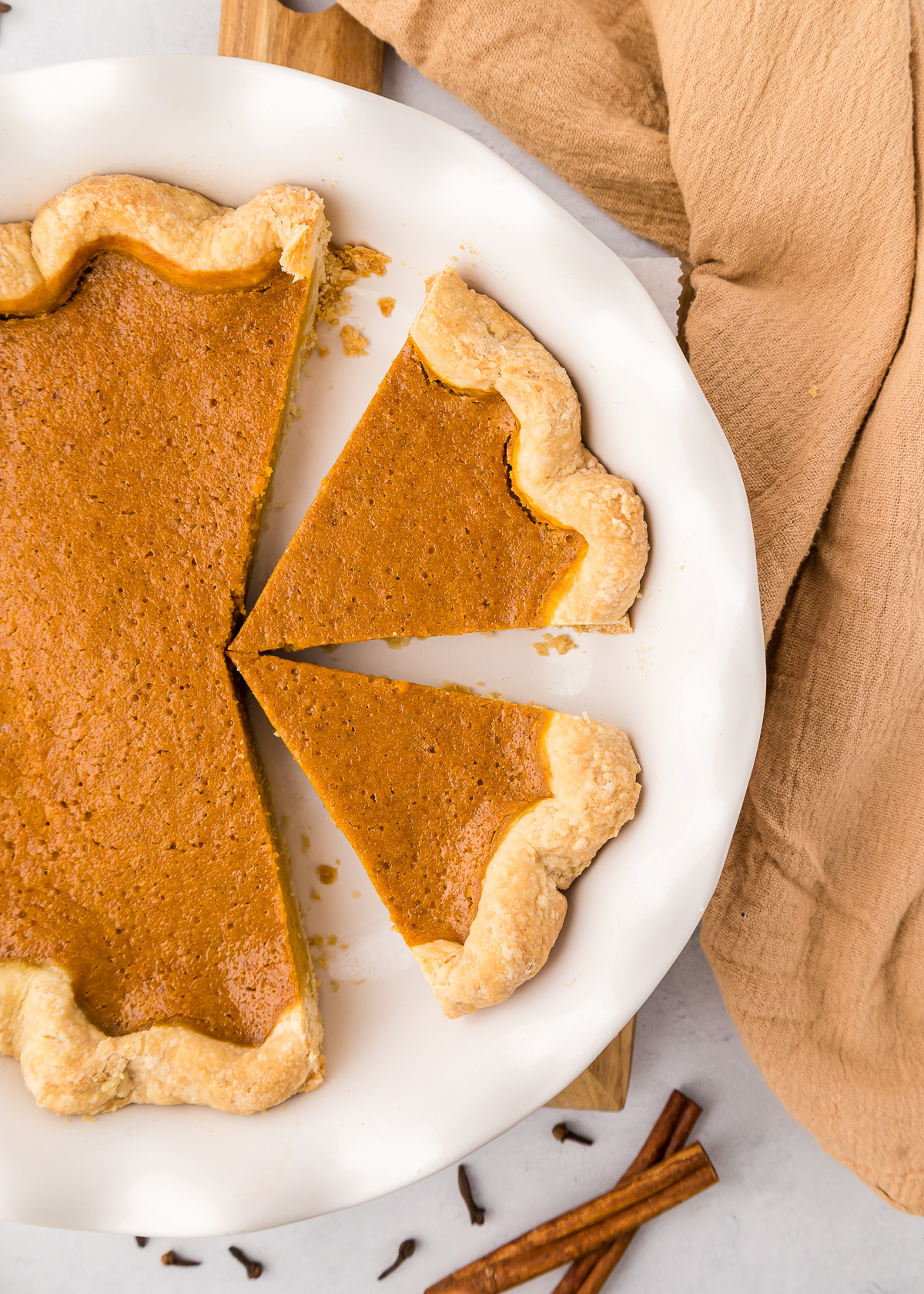 Overhead shot of a pumpkin pie with one slice cut and lifted from the flaky crust.